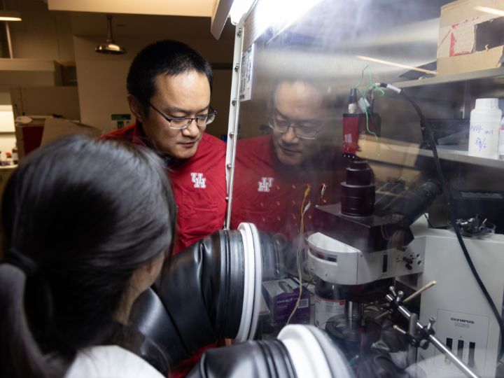 As Assistant Professor Xiaonan Shan observes, recent UH graduate Guangxia Feng works on the operando reflection interference microscope (RIM) inside a “glove box,” since the lithium-ion battery electrolyte is flammable.