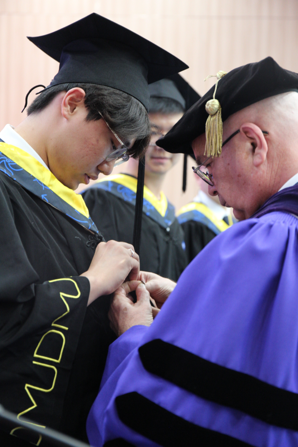 One of the representative students having his UH pin placed by Dr. Ballarini.