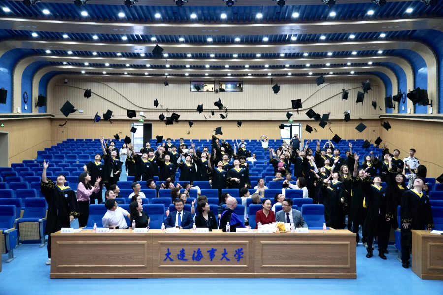 Students throwing their graduation caps into the air. The front row consists of faculty, administration and staff of DMU-UH Institute.
