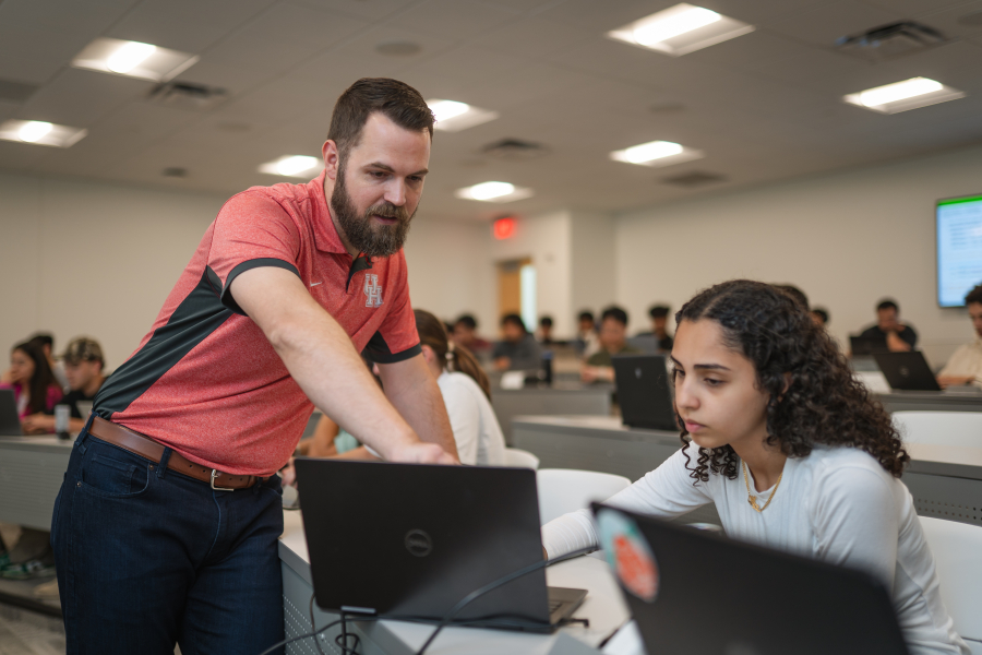 Zelisko, left, points at the laptop screen of a student, right, in a full lecture hall. 