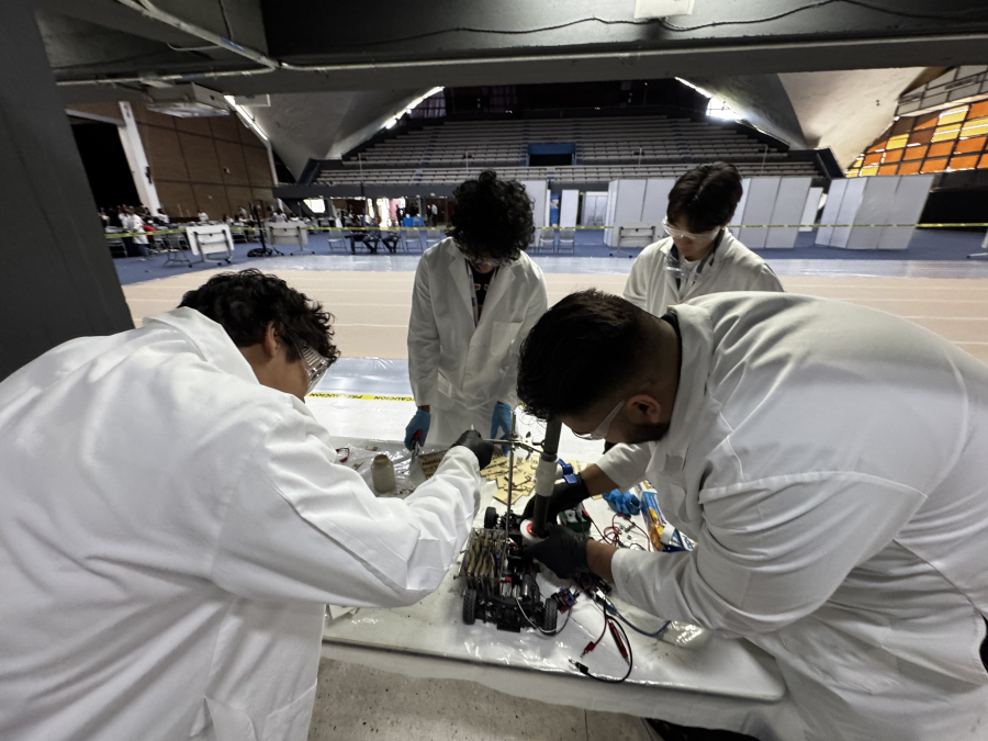 In AIChE Chem-E-Car Competition, team members must design and construct a chemically powered vehicle within certain size constraints to travel a specified distance using only chemical processes to run and stop.