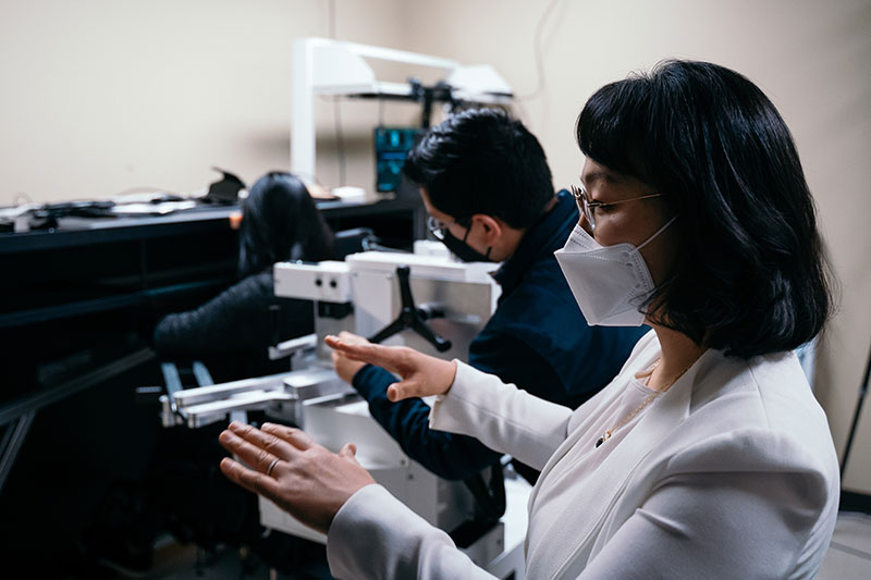 Jinsook Roh guides students in using lab equipment. 