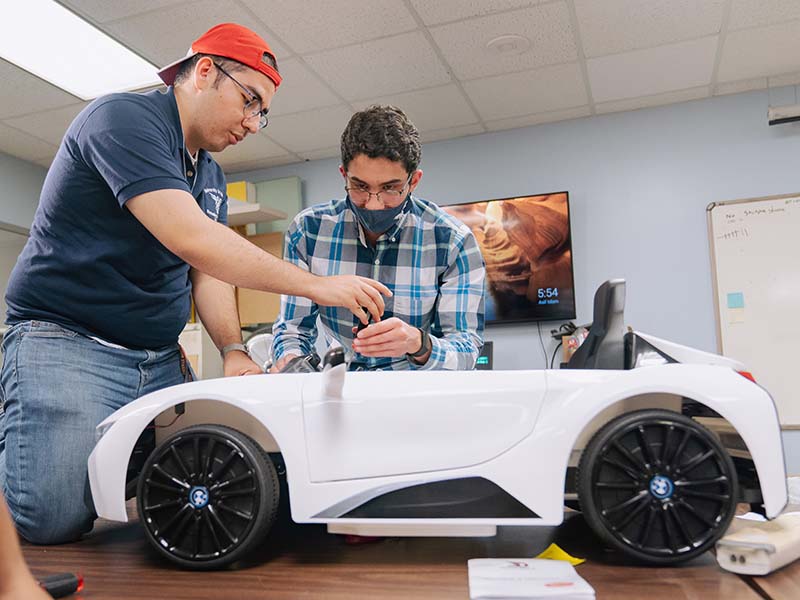 Rogelio Castilla and Omar Nofal work on car electronics.