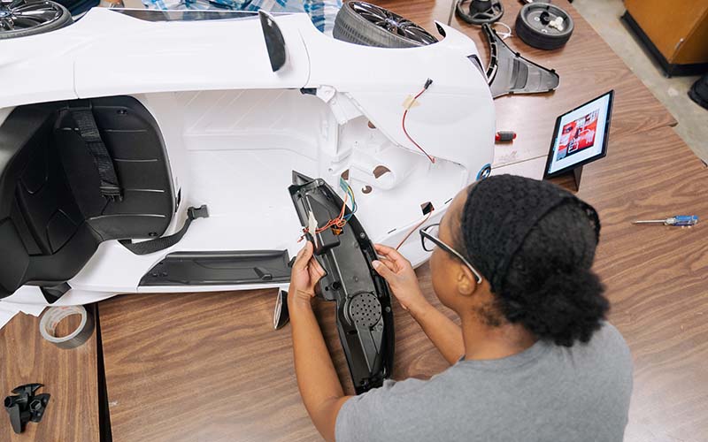 Jasmine Dhaliwal deconstructs the steering wheel. The group moved a pedal button to the steering wheel so the car could be operated without feet.