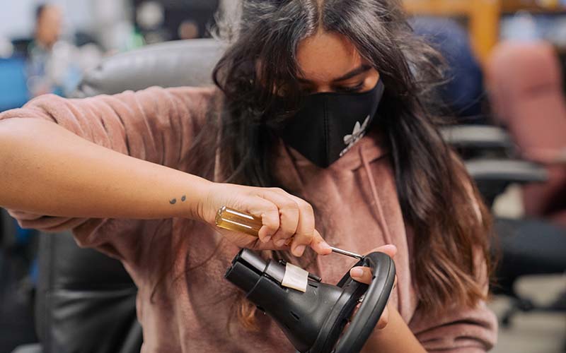 Jasmine Dhaliwal deconstructs the steering wheel. The group moved a pedal button to the steering wheel so the car could be operated without feet.