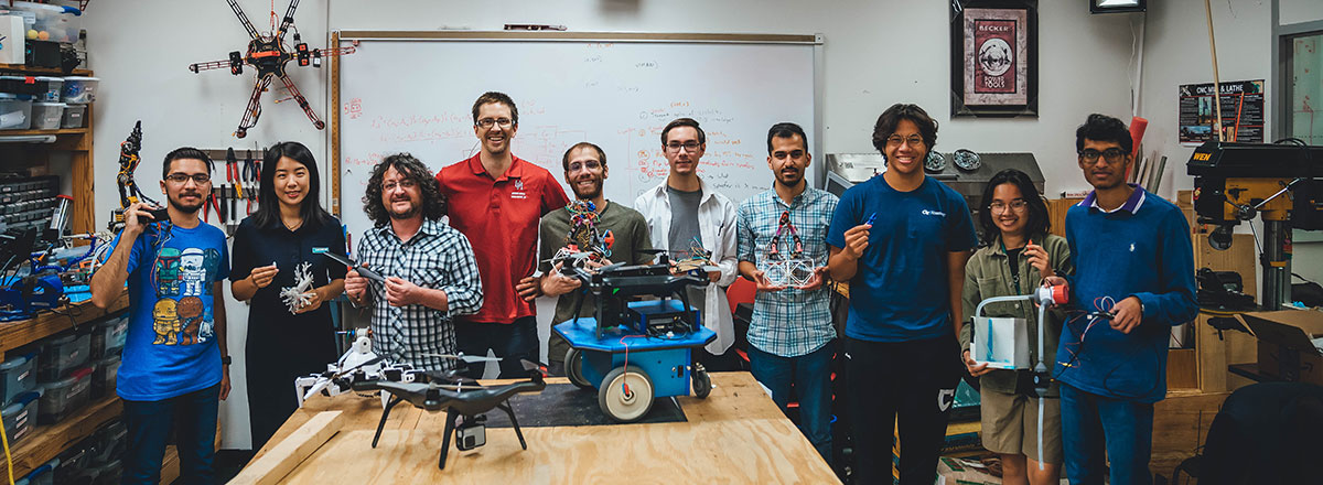 Aaron Becker and his research students all displaying their favorite robots.