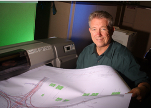 UH Civil Engineering Alumnus C. Rick Coneway holds a KBR design drawing for a TxDOT highway interchange. Photo by Jeff Shaw.