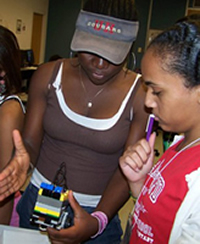 GRADE Camp mentor, Bose Olomola, teaches Kristine Singleton about how to read the infrared sensor measurements on her robot. Photo by Jeff Shaw.