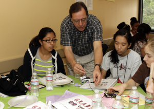 Associate professor Len Trombetta works with GRADE campers on creating speakers in styrofoam plates.