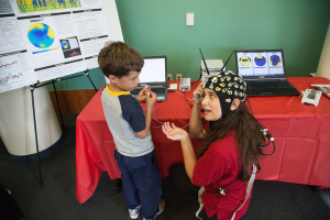 Undergrad researcher Anastasiya Kopteva shows off her innovative research to young STEM enthusiast.