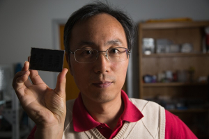 Associate Professor Jiming Bao and screen filled with graphene flakes suspended in solvent between two layers of glass. Bao discovered that a magnet rotates and aligns the flakes.