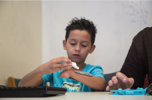 8-year-old Rafael tries on pieces of his gift - a new hand from UH students