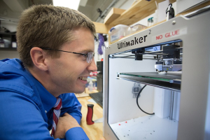 In his lab, Becker watches 3-D printer where many of his robot parts are made