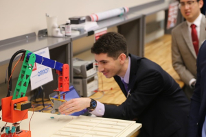 A UH electrical and computer engineering student demos the sorting robot for Omron representatives.