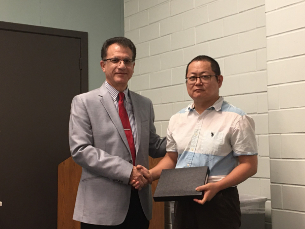 Heidar Malki, Senior Associate Dean of the Technology Division, presents Weihang Zhu, professor of Engineering Technology, with the Faculty Research Excellence Award.