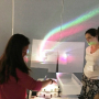 Gwen Musial, (second from right) watches as students use a prism to split white light into a rainbow