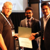 FlexSim CEO Bill Nordgren presents an award to University of Houston graduate students Muhammad Zia-ul-Haq Hussain and Moaz Ahmed for their third place finish at the annual Healthcare Systems Process Improvement Conference.