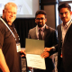FlexSim CEO Bill Nordgren presents an award to University of Houston graduate students Muhammad Zia-ul-Haq Hussain and Moaz Ahmed for their third place finish at the annual Healthcare Systems Process Improvement Conference.